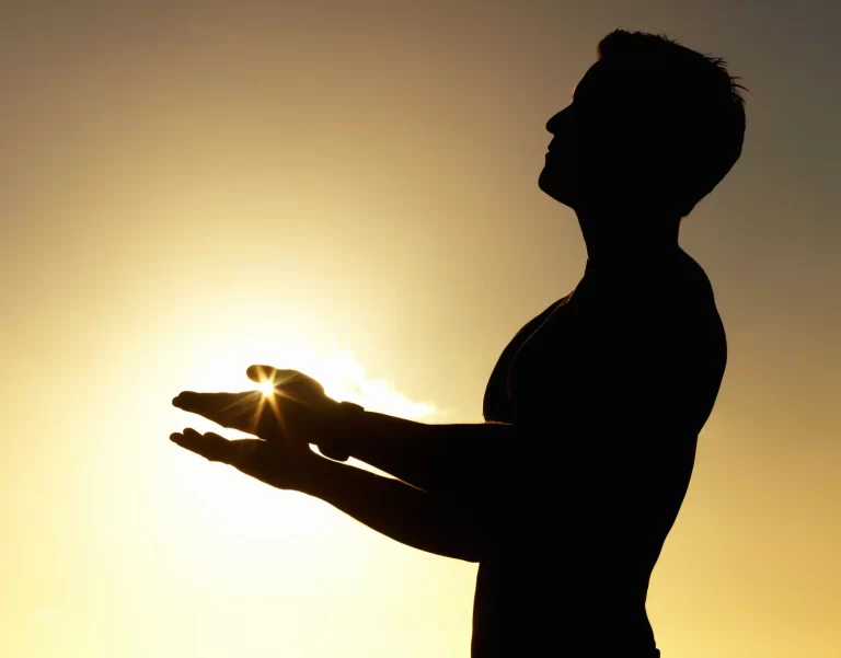 A silhouette of a man with light reflected to his hands