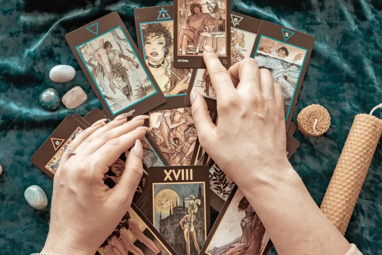 A top view image of a hand placing the tarot cards on the table.