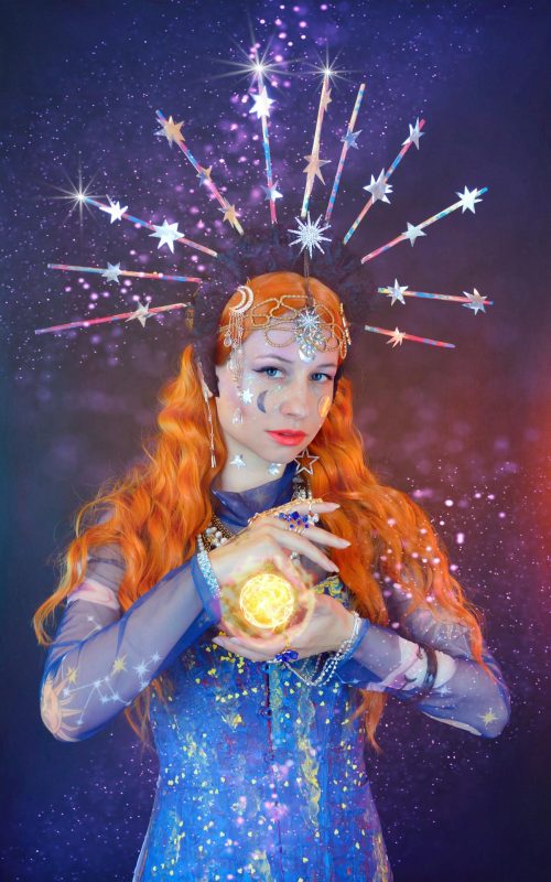 A redhead woman with astrology costume based aesthetic colors and items while holding an energy ball